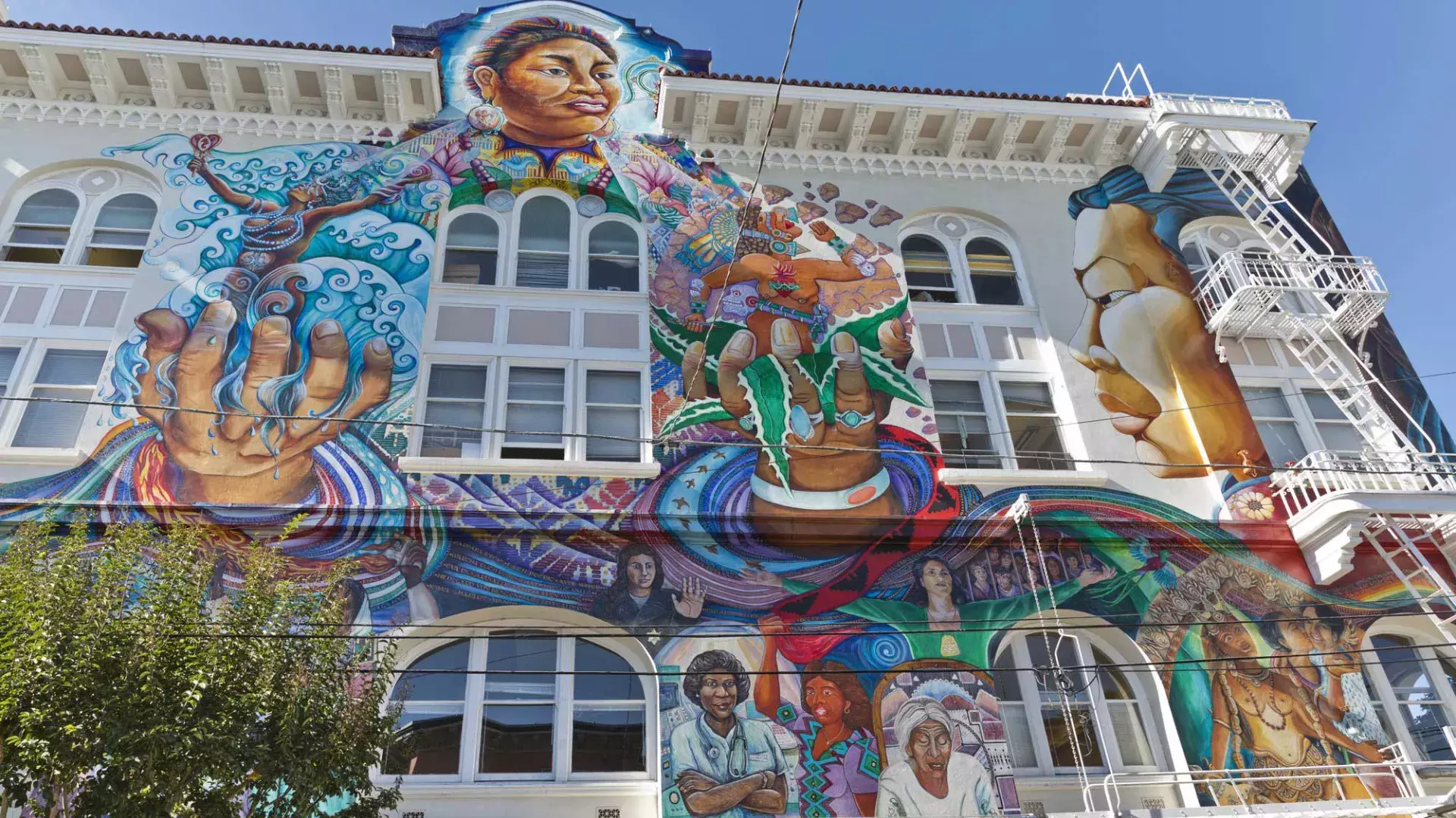 A colorful, large-scale mural covers the side of the Women's Building in San Francisco's Mission District.