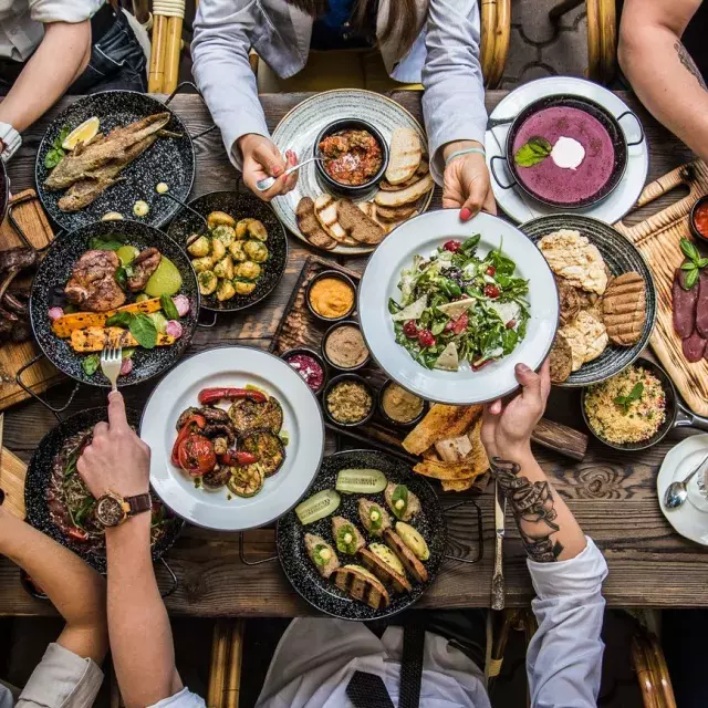 People sitting at a dining table, sharing food.