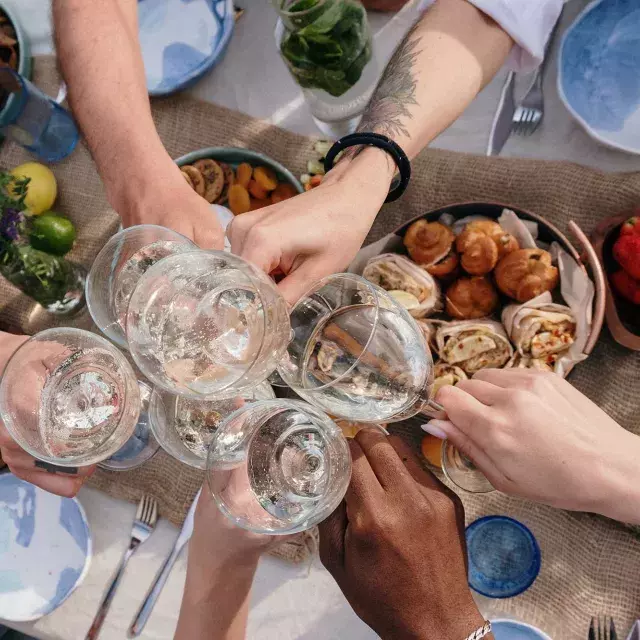 Overhead shot of a group of people clinking glasses at a brunch table.